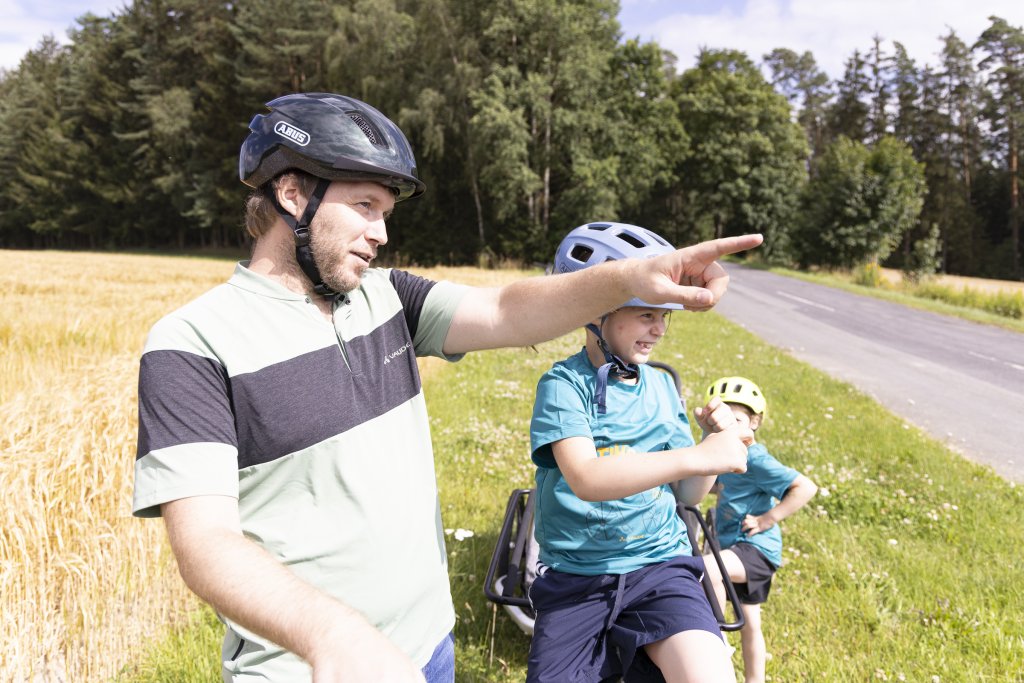 Mann steht mit Fahrrad vor Getreidefeld und es ist sonnig.